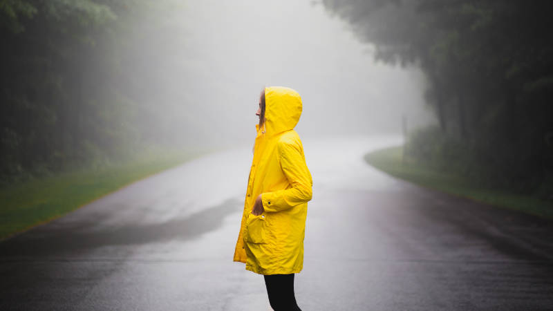 Frau im Regen mit einer gelben Regenjacke