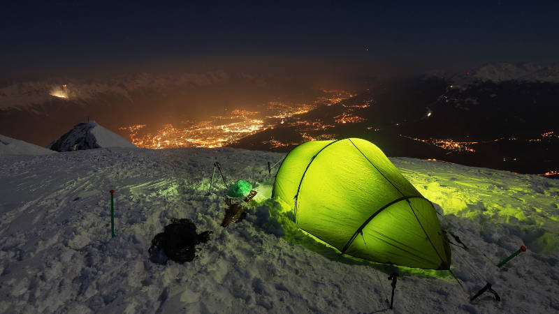 Wintercamping-Zelt auf schneebedecktem Berg in der Nacht.