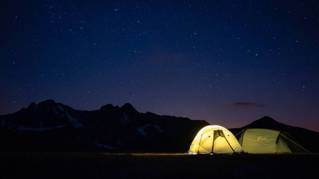 Ein gemütliches Zelt im Gebirge unter einem sternenklaren Himmel.