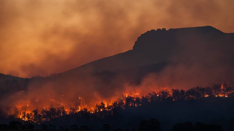 Eine feurige Flamme verschlingt einen schroffen Berg.